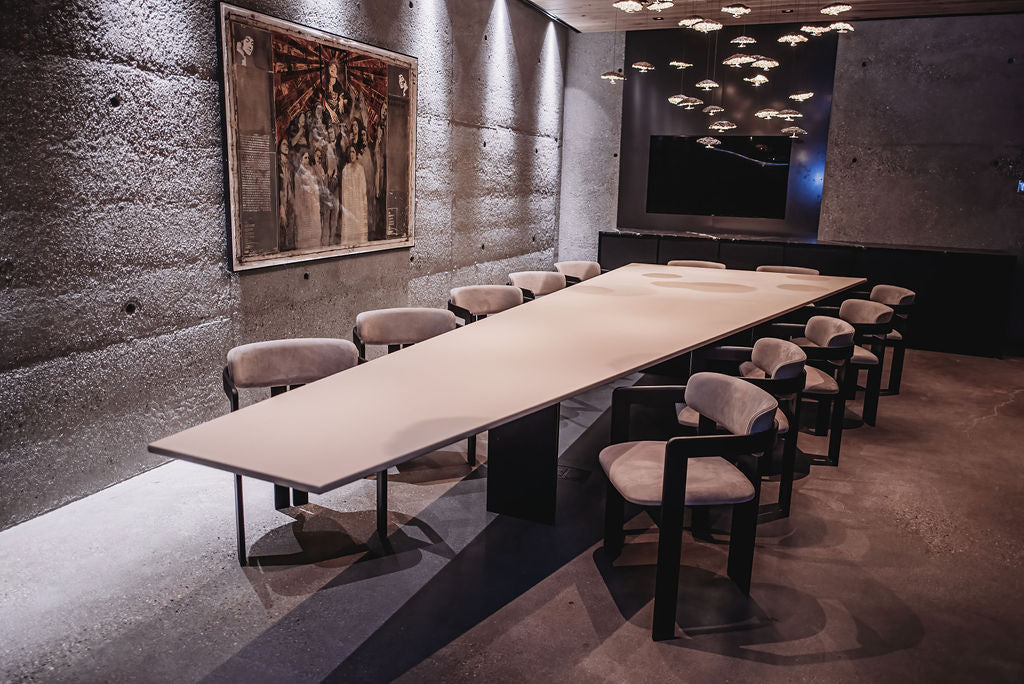 Modern conference room with long table and chairs against a textured wall. BWP Spaces bespoke furniture and millwork at Checkmate Winery, BC