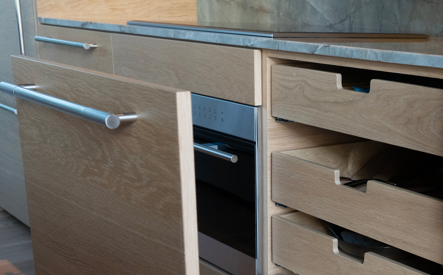 Close-up of a kitchen cabinet with drawers and an oven. Minimalist private residence with custom millwork by BWP Spaces
