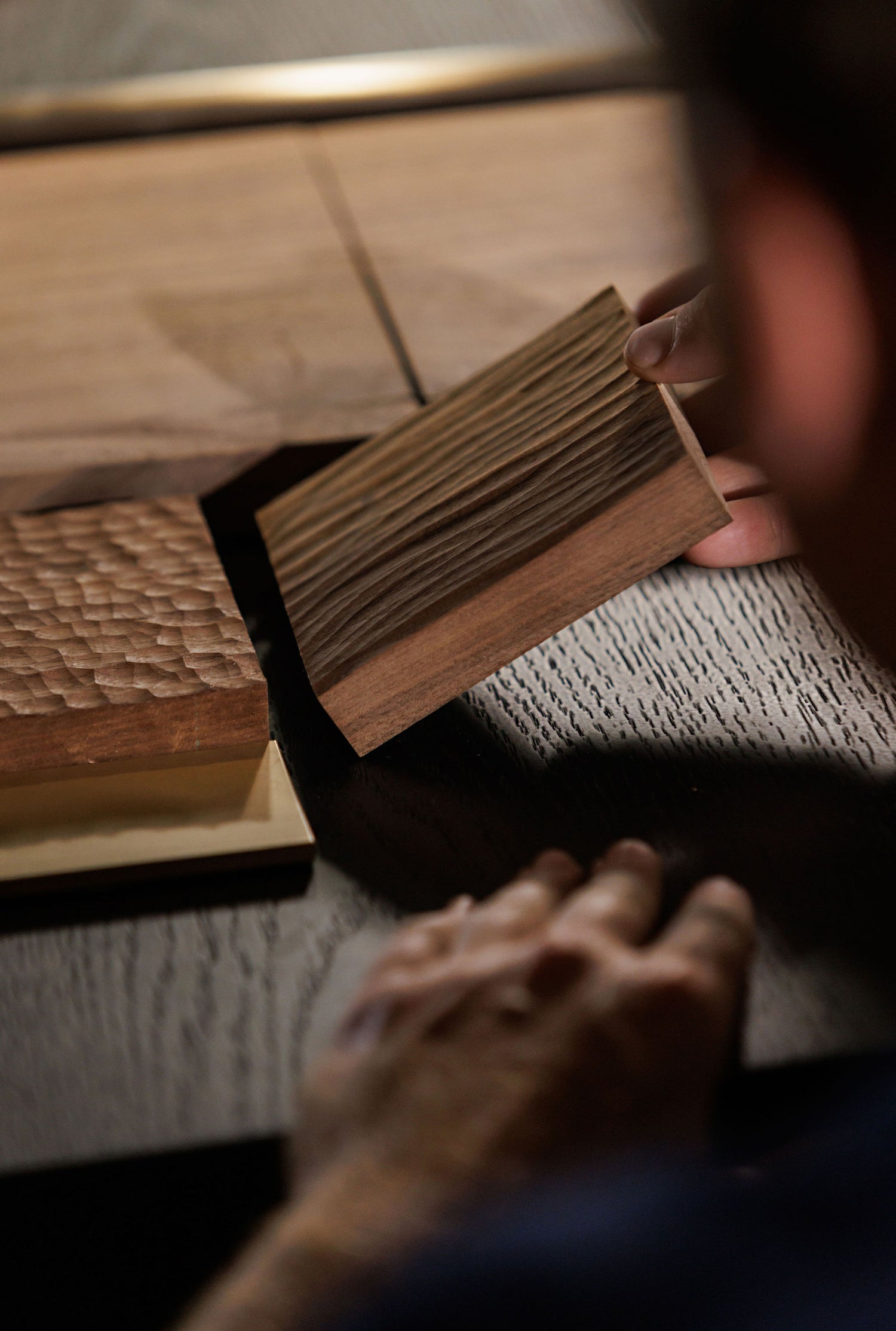 BWP Spaces, Millwork Kelowna BC. Close-up of a hand holding a wooden block with a textured surface.