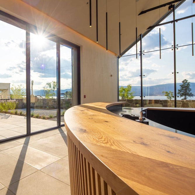 Interior of CedarCreek Estate Winery featuring custom oval tasting bar and retail shelving by BWP Spaces in collaboration with Erin Martin Design and Arcanum Architecture
