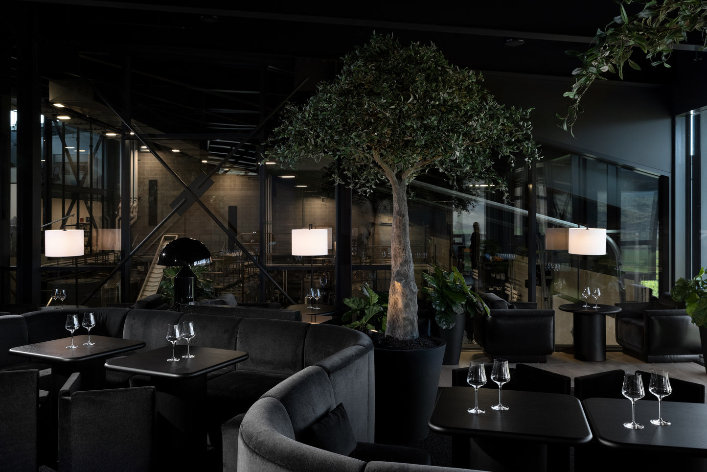 Checkmate Winery tasting bar and custom millwork by BWP Spaces, South Okanagan. A sleek modern wine tasting lounge with dark furniture and large windows looking out onto a scenic landscape.
