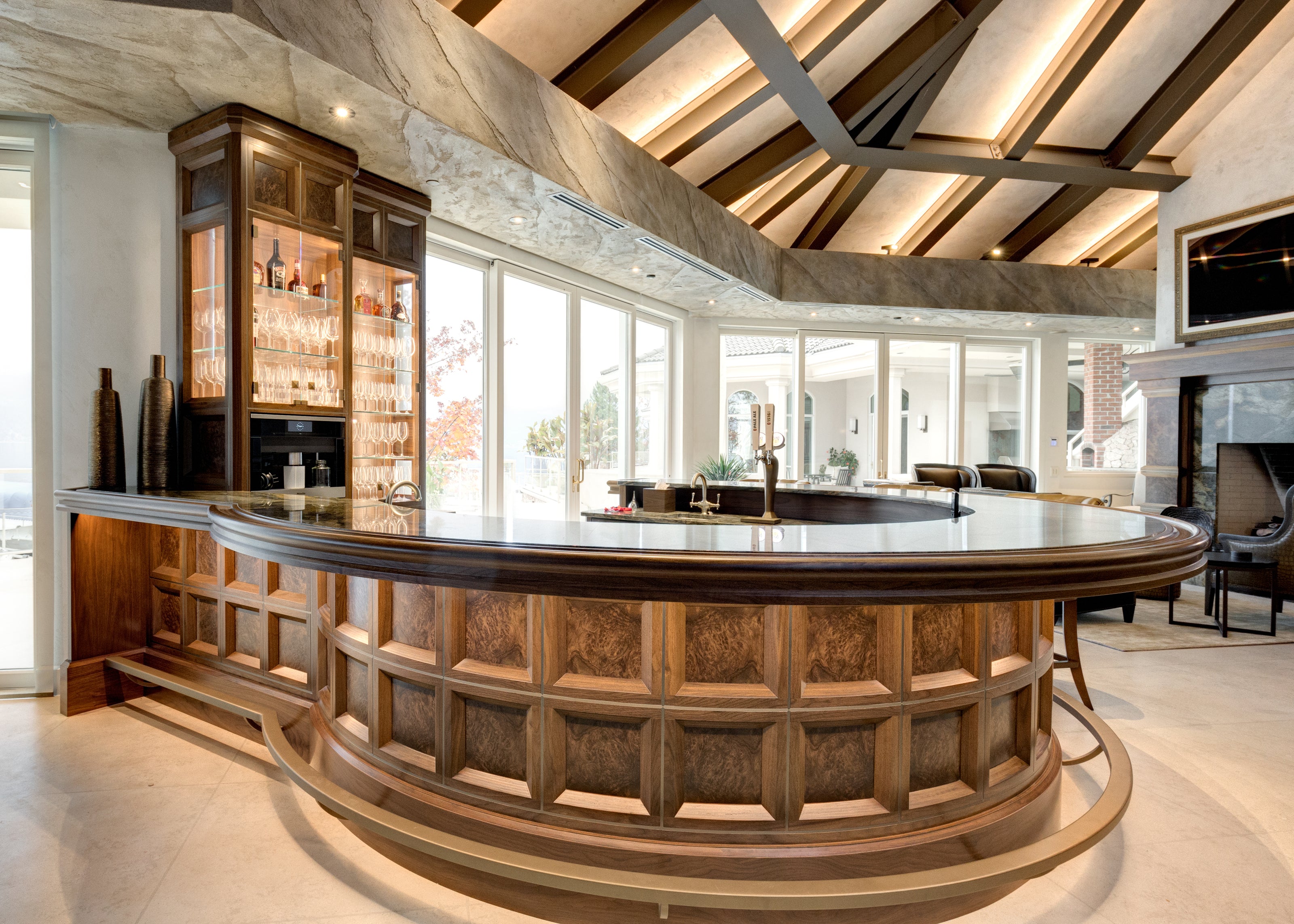 A luxurious curved wooden bar with a high ceiling and a glass display cabinet.